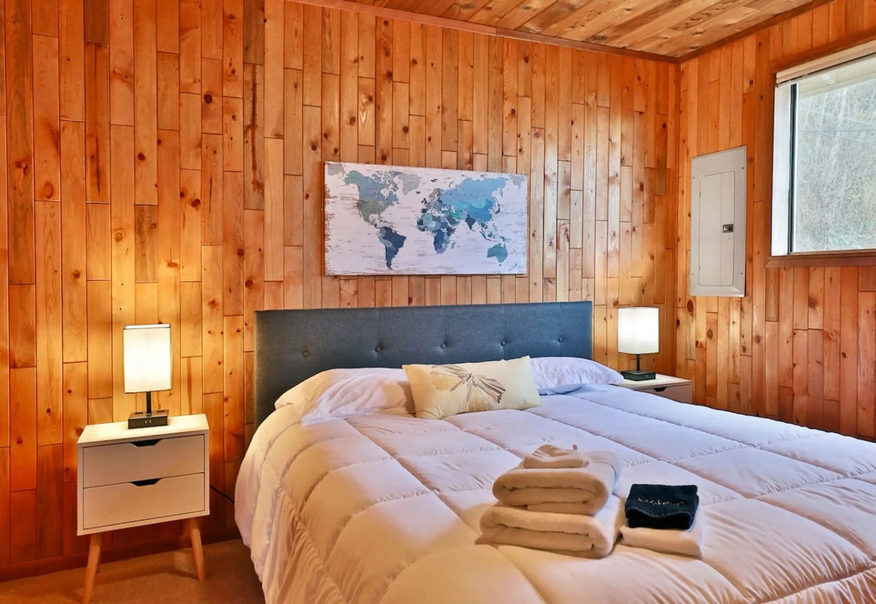 Bedroom with king bed and world map art on cedar walls