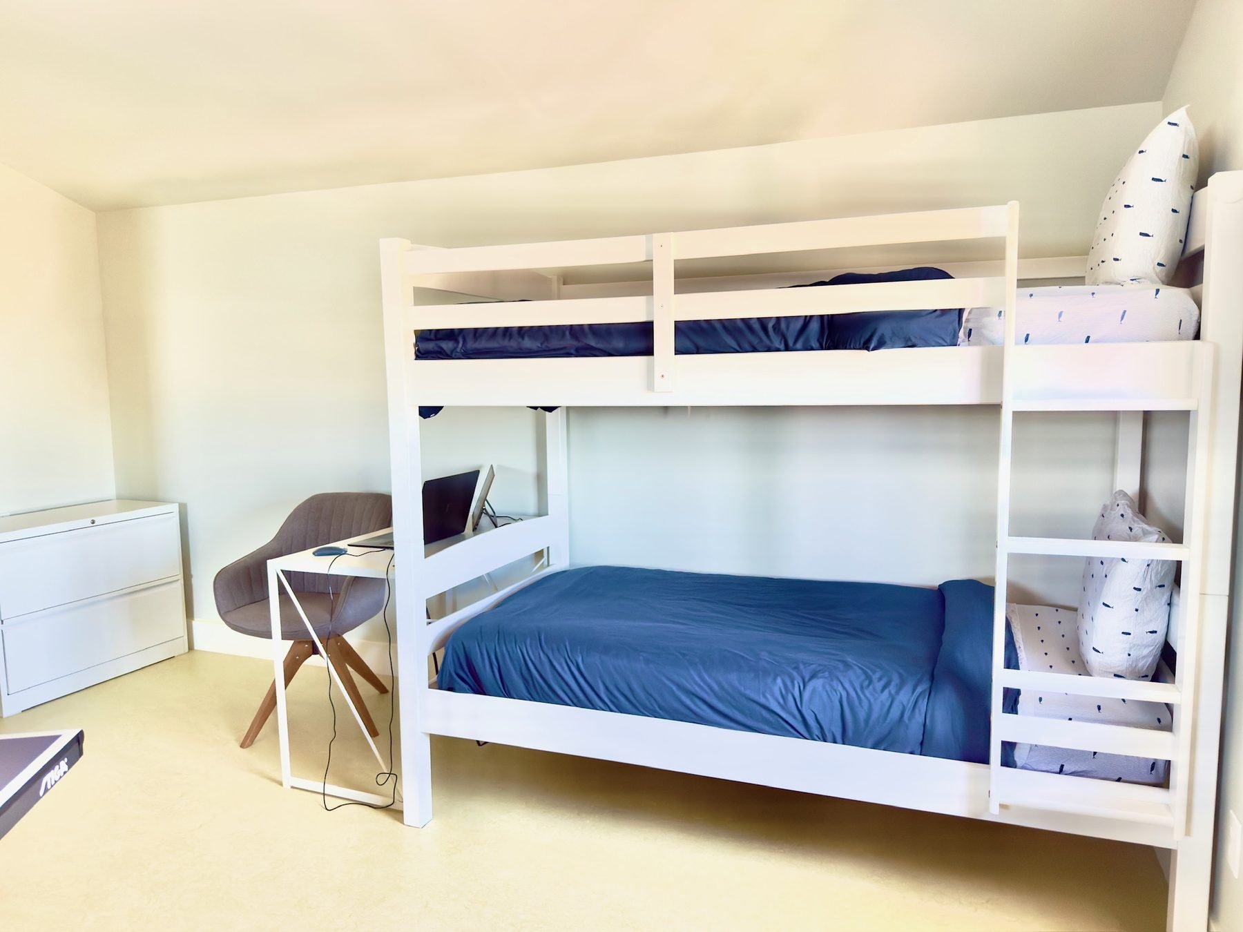 Bunk room with white bunk beds and navy bedding for kids