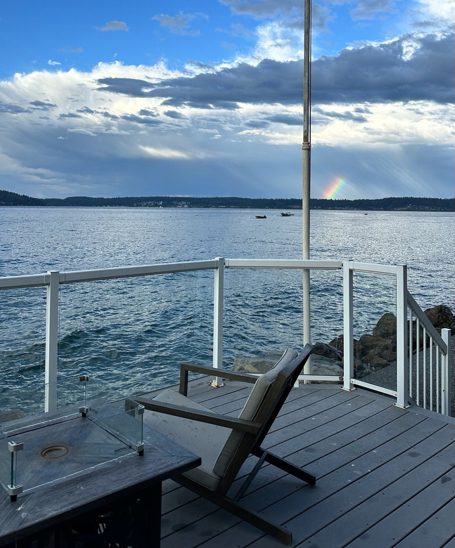 Deck with Adirondack chair, fire pit, and rainbow over the water