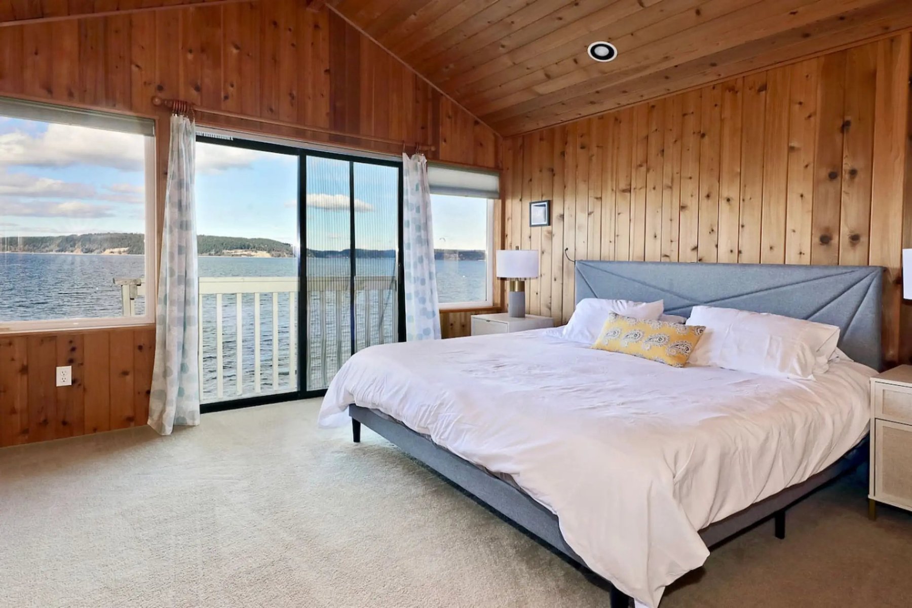 Master bedroom with king bed, cedar walls, and sliding door to water-view balcony